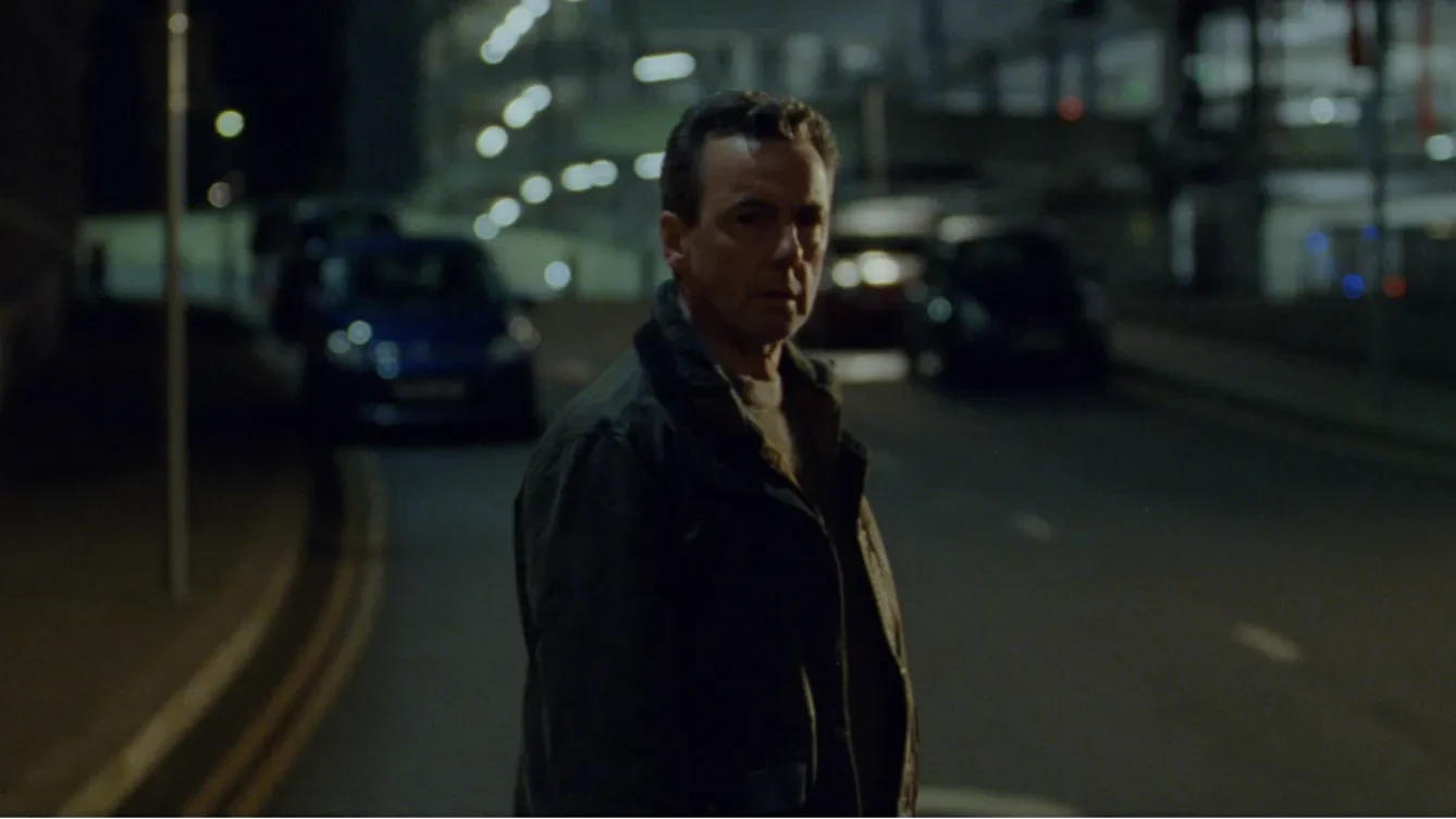 A man stands in the middle of a road at night