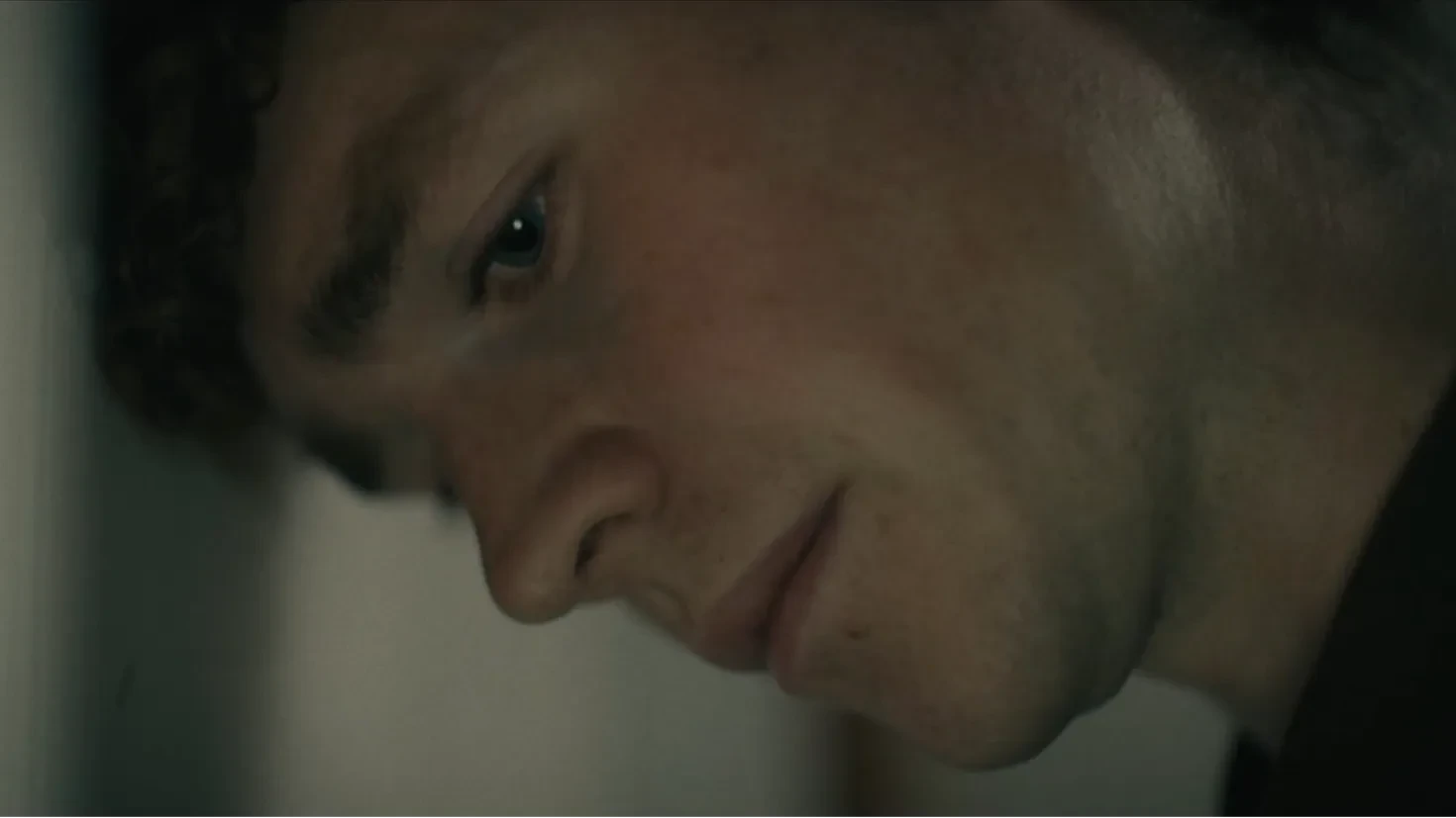 A pensive looking man leans his head against a wall.