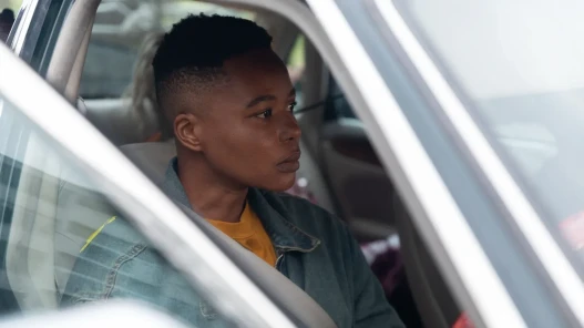A transmasc driver sits in their car staring out of the window