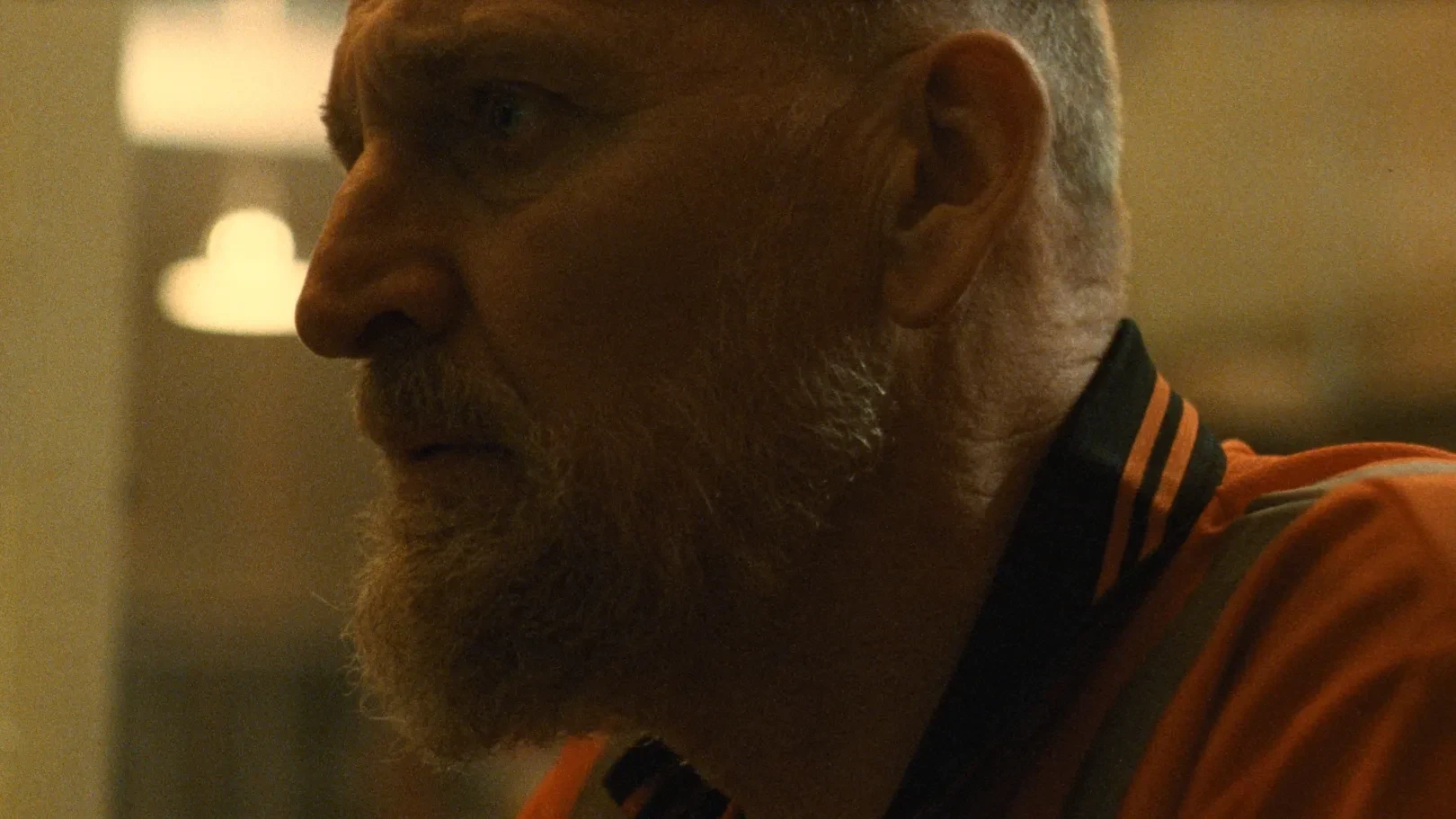 Close up side profile of a man in an orange sweatshirt