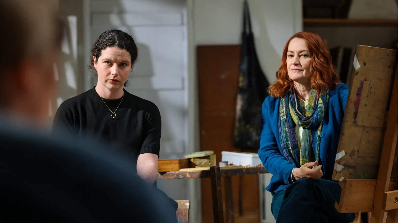 Two women observe a life model in a community art studio.