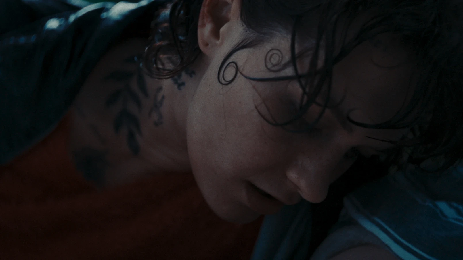 A woman with spirals in her hair leans on a man's chest.