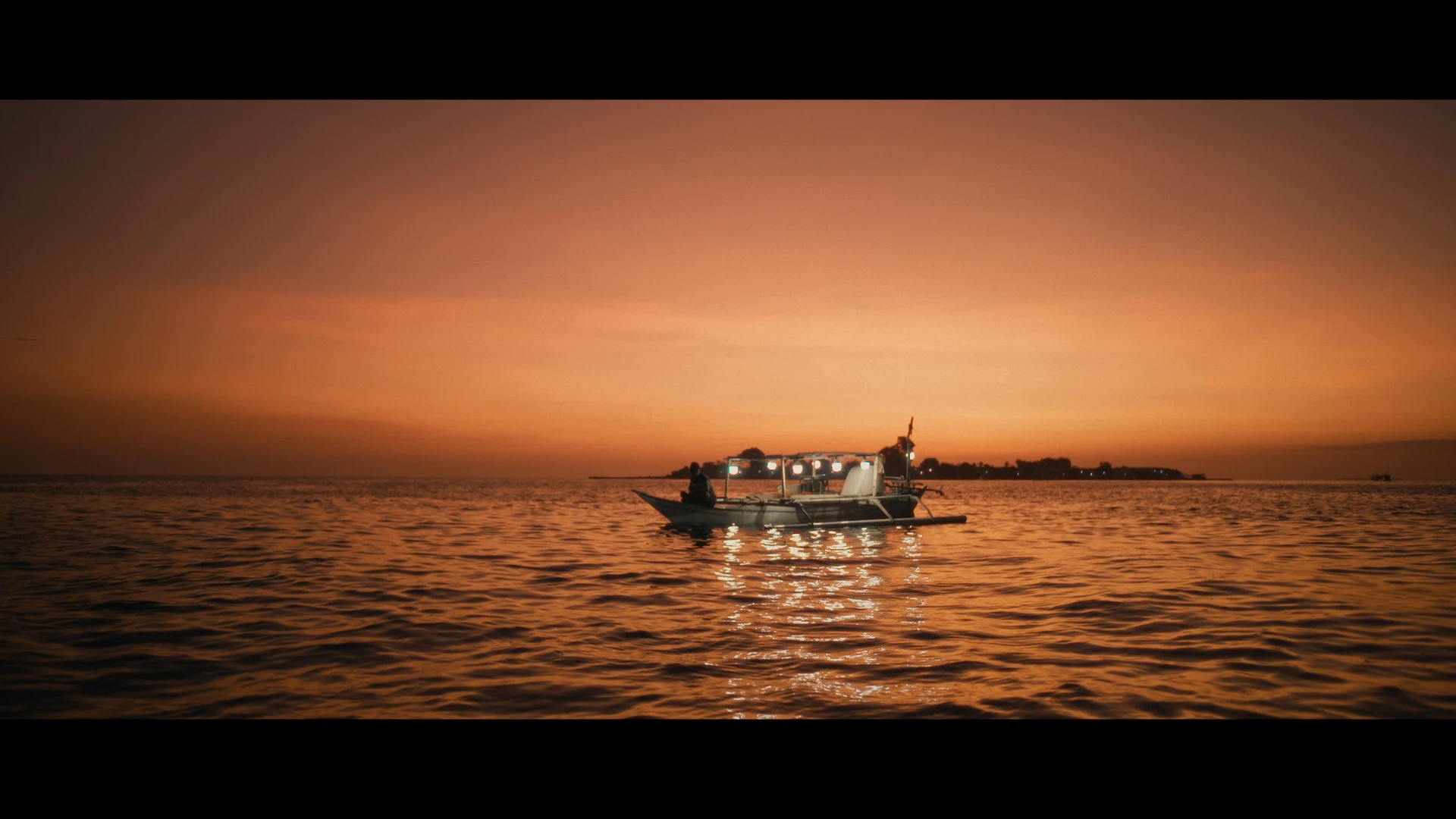A squid fisherman on his boat during dusk,  Salisi' Besar Reef, Indonesia