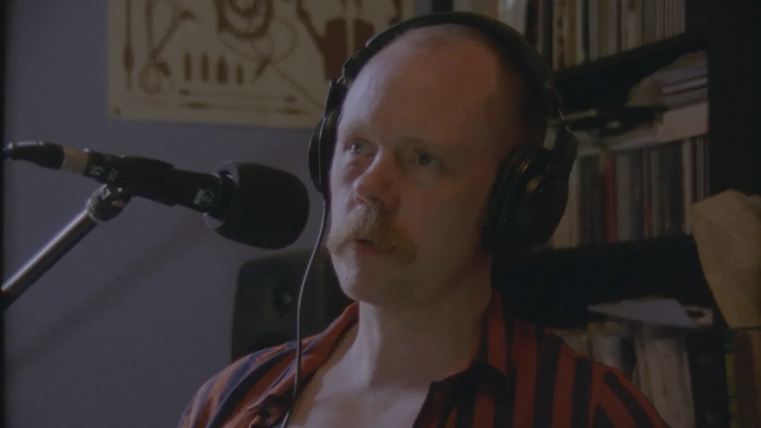 The artist and academic Conal McStravick speaks into a mic about a lost film by Stuart Marshall
