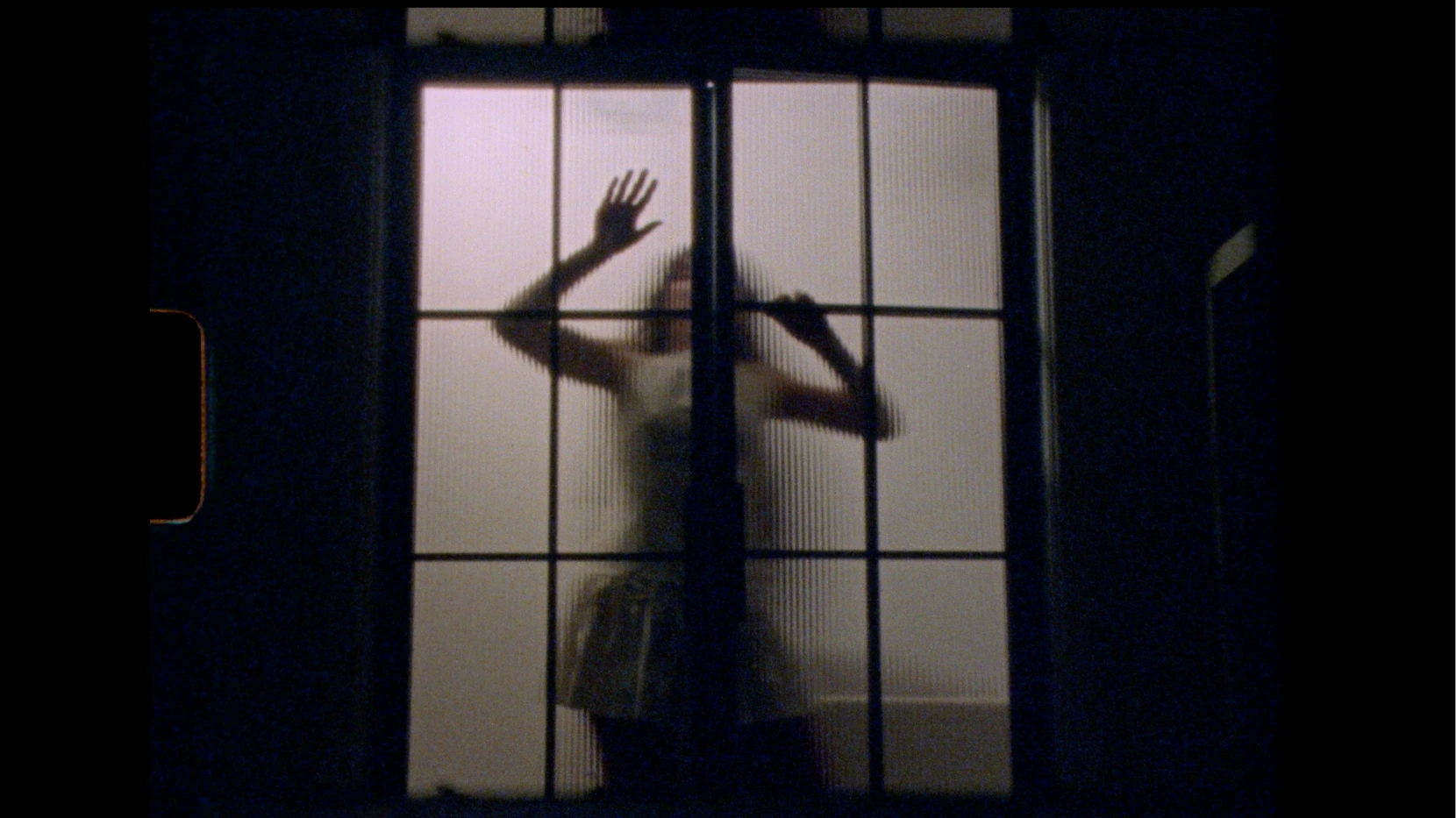 Woman leans against an opaque panelled door.