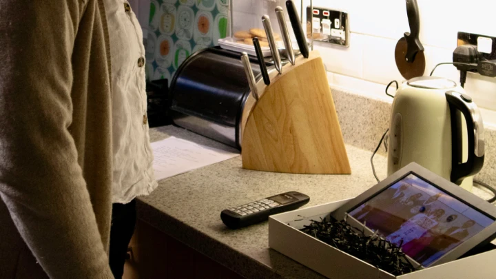 A digital picture frame on a counter next to a set of knives