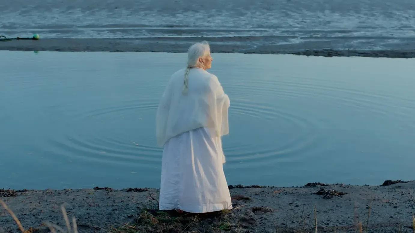 A woman throws stones into the creek at sunset