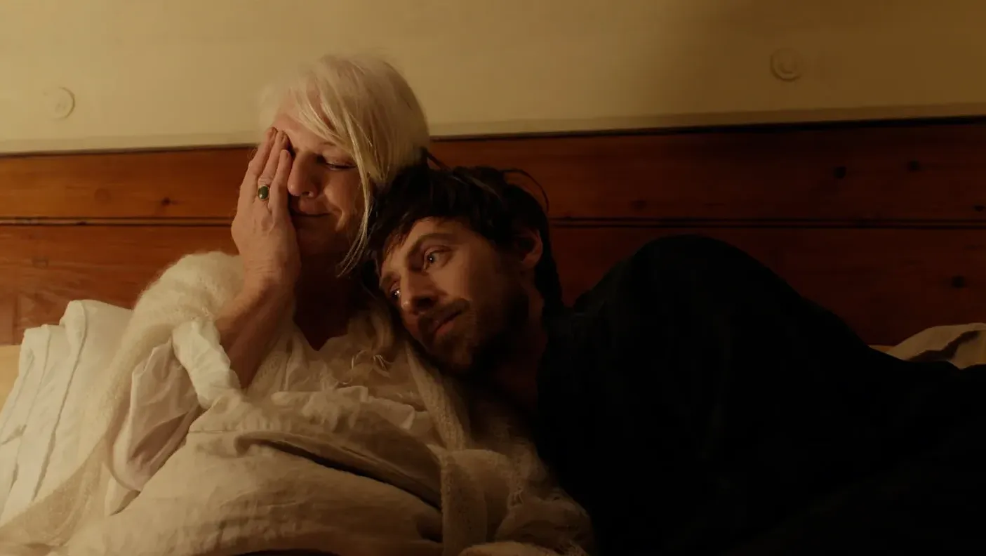 A woman and a man lie on a bed together.