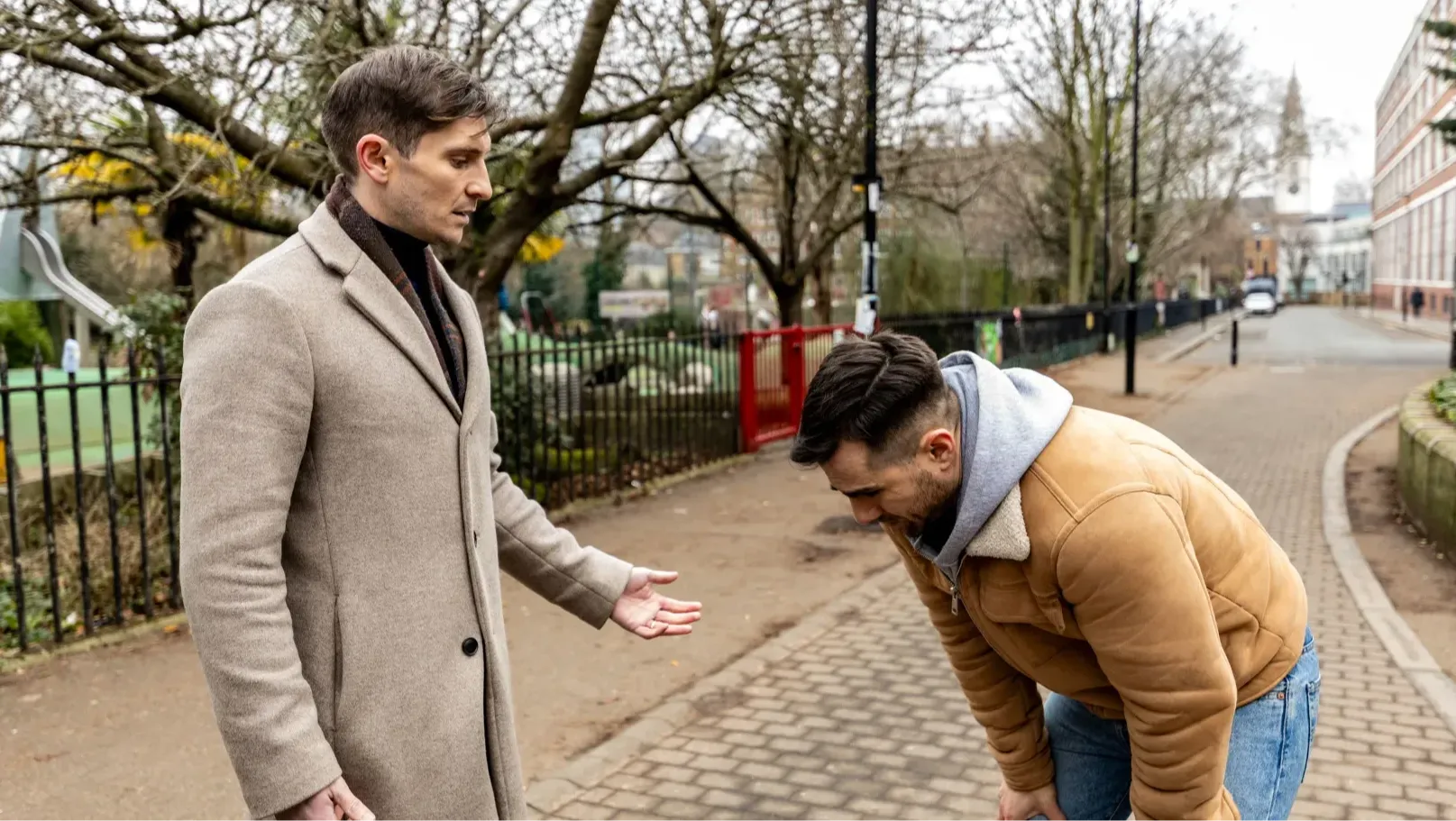 A man looks at another man as he has a panic attack in the street.