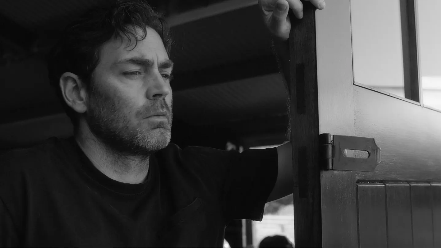 A man standing at garage door, looking forlorn.