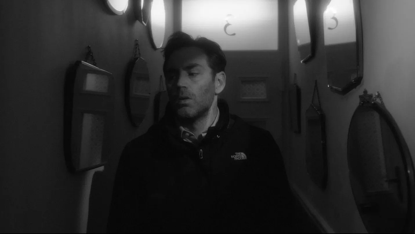 A man walking through a mirrored hallway.