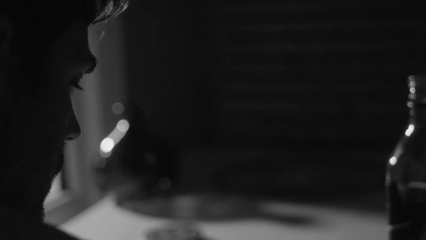 A man sat drinking at kitchen table late at night.