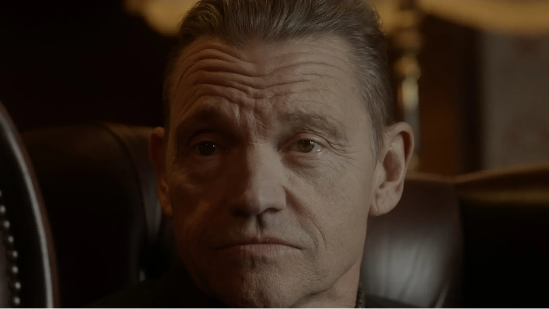 A man sat in an armchair staring just off camera at someone else