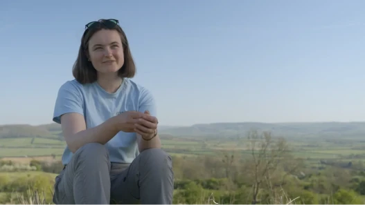 A young farmer, Lucy Robbins, speaking to camera in a spring field in the Cotswolds