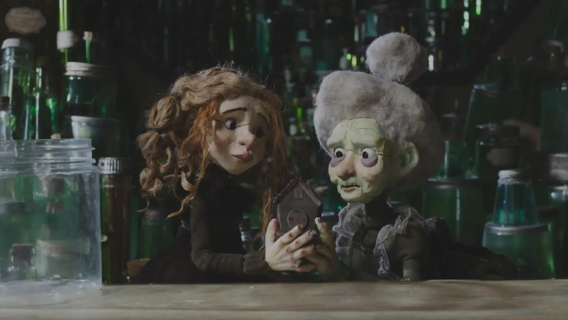 Two puppets (a younger and an older one) holding a clock surronded by jars