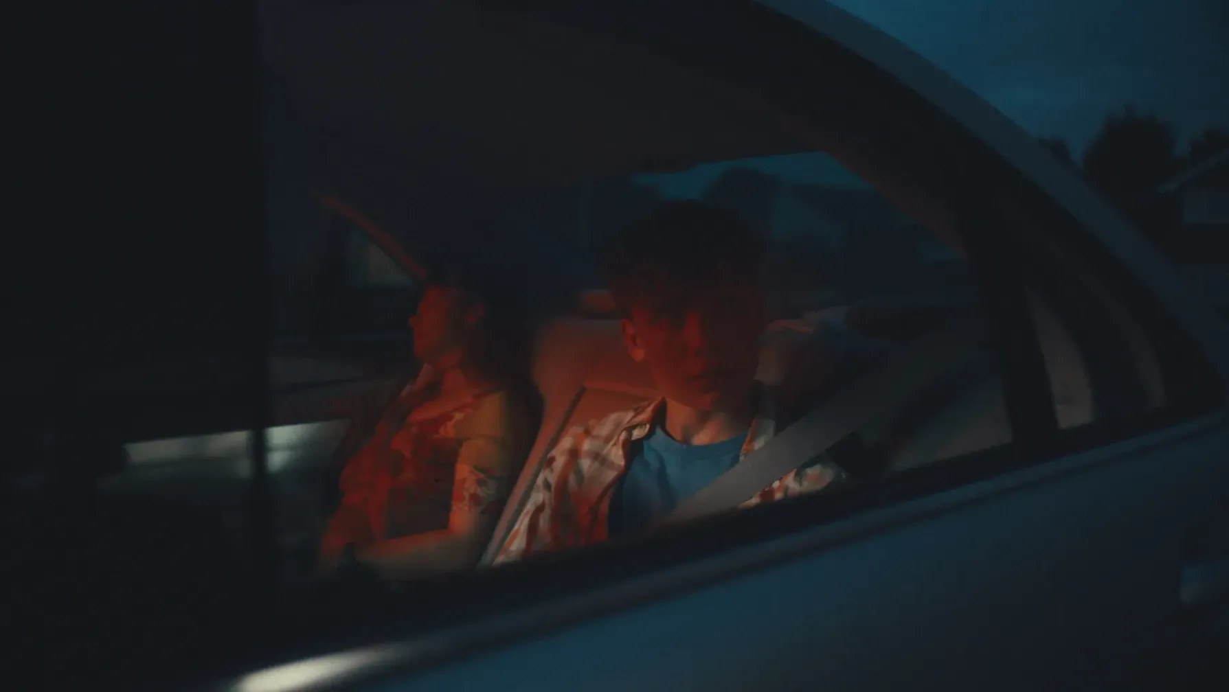 A teenage boy looks outside of the car window