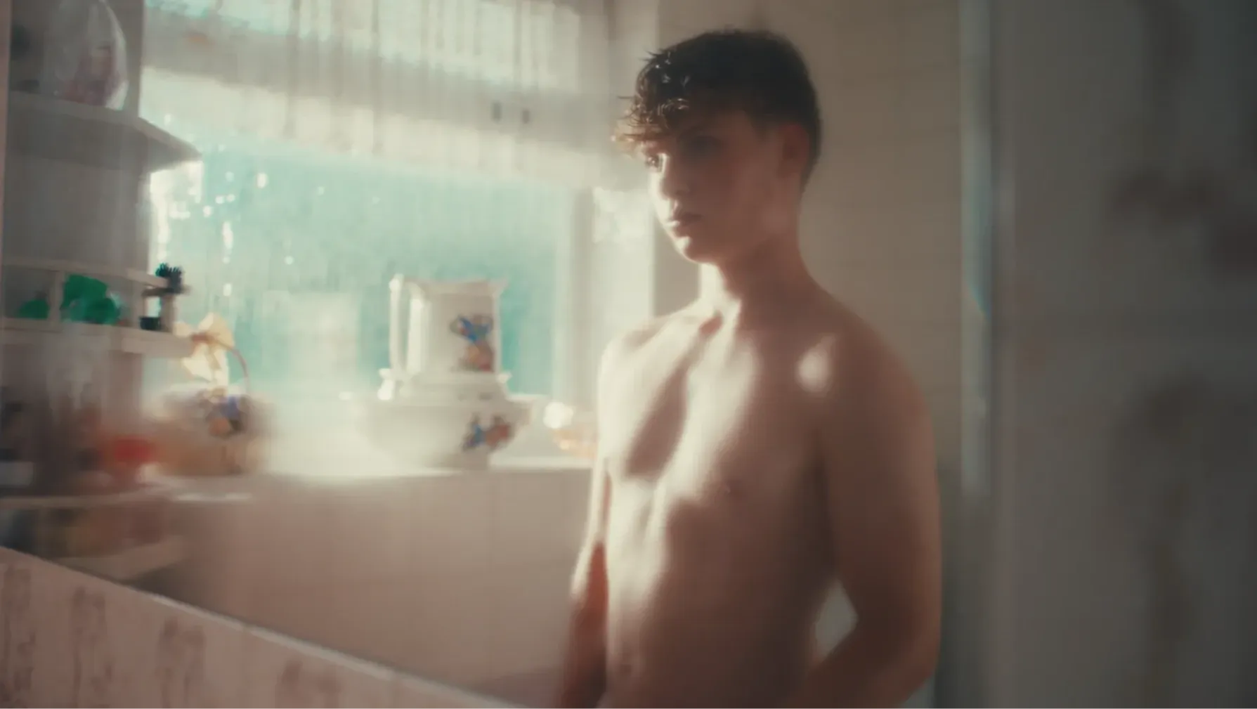 A teenage boy looks at himself in the mirror