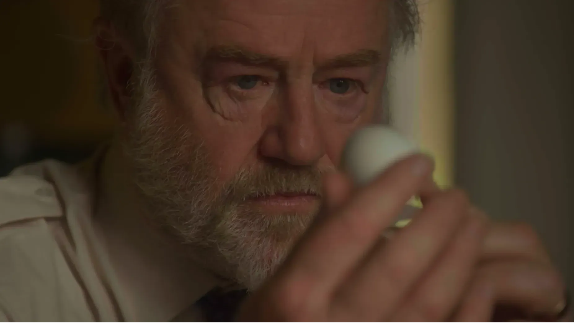 An older man examines an eggshell