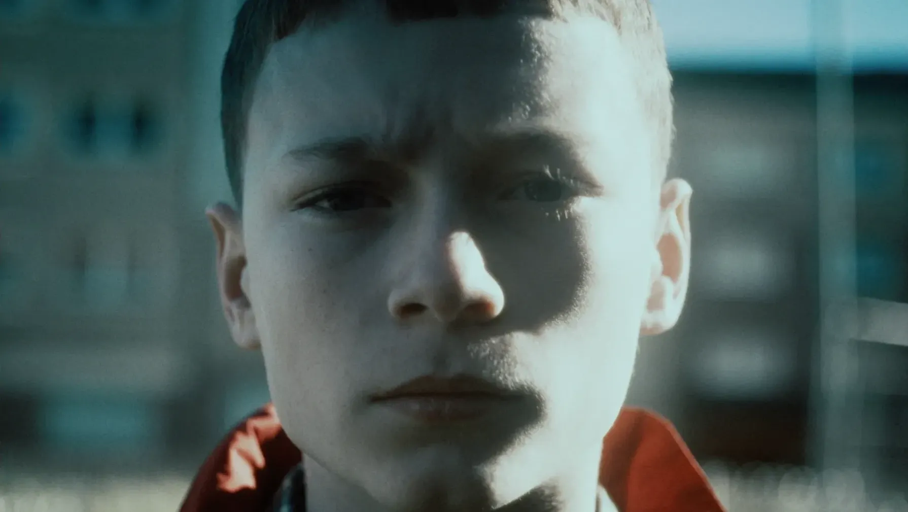 A young boy with close cropped hair and a stern look stares at the camera.