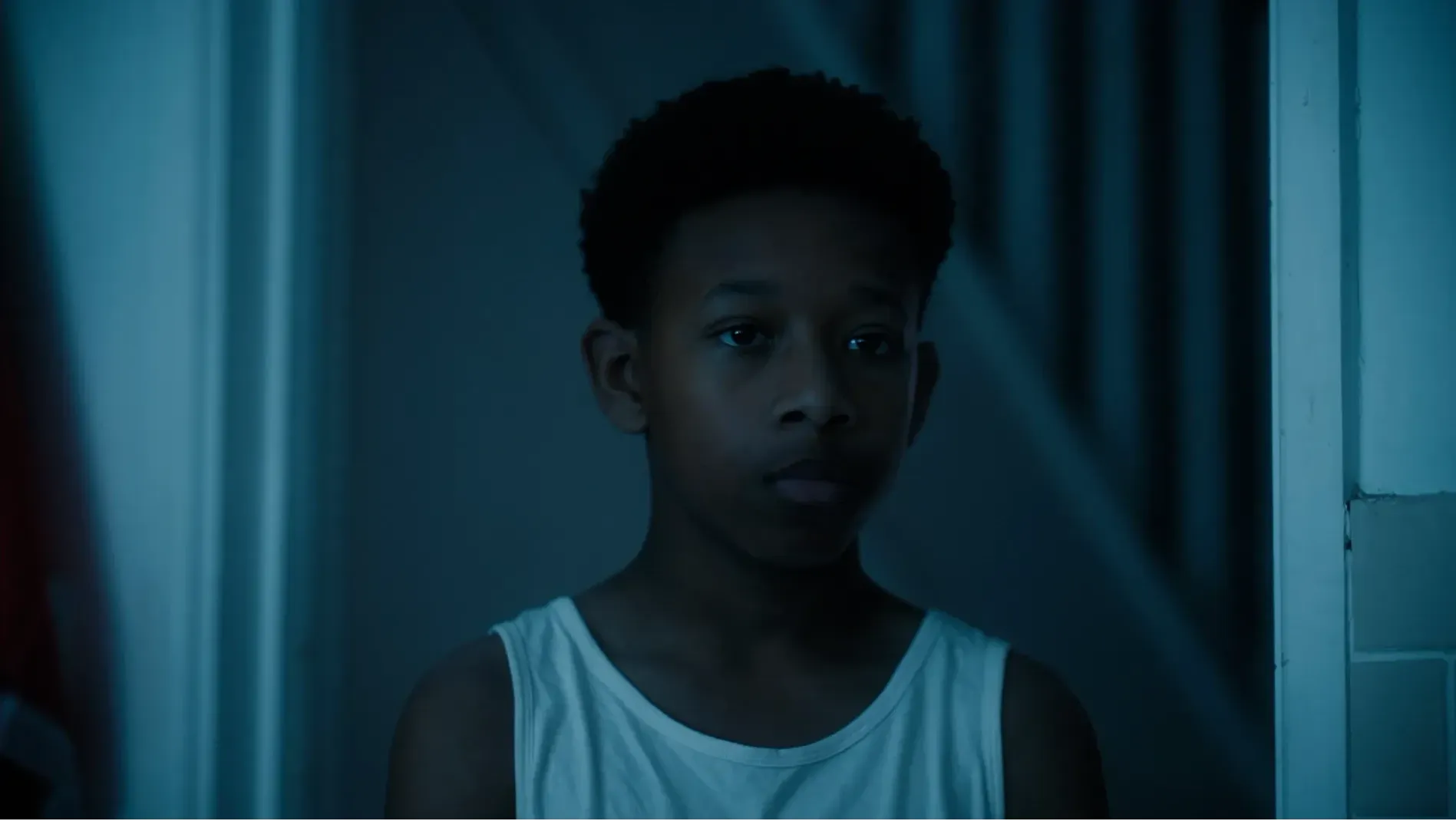 A young boy stands in a domestic doorway