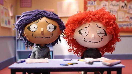 Two worried-looking school children sit in a classroom together. 