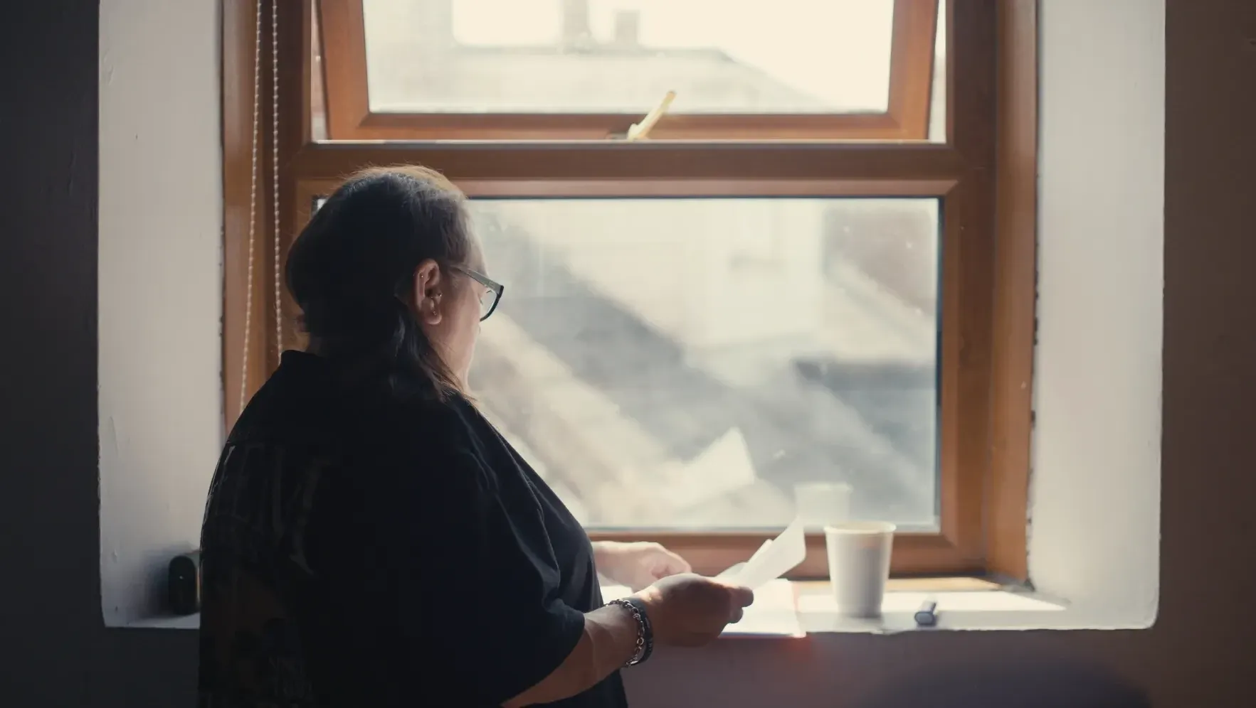 A woman reading through script by a window