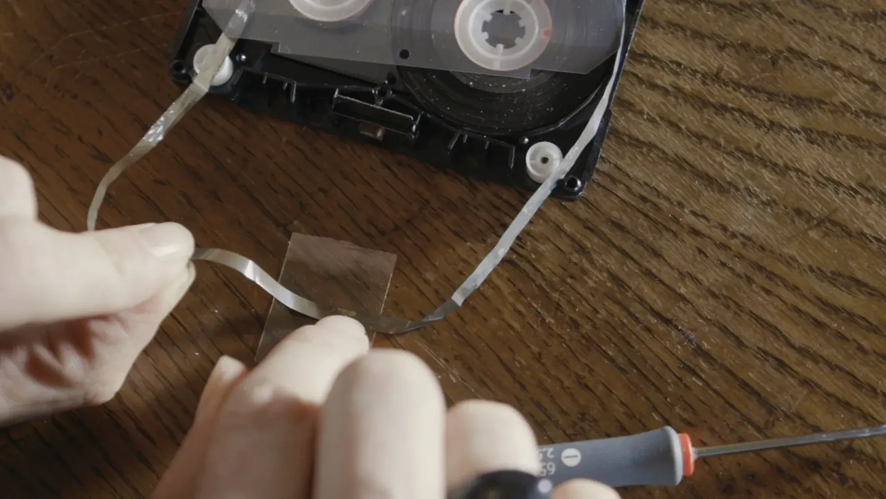 The film's director repairing a found audio tape that has been severed