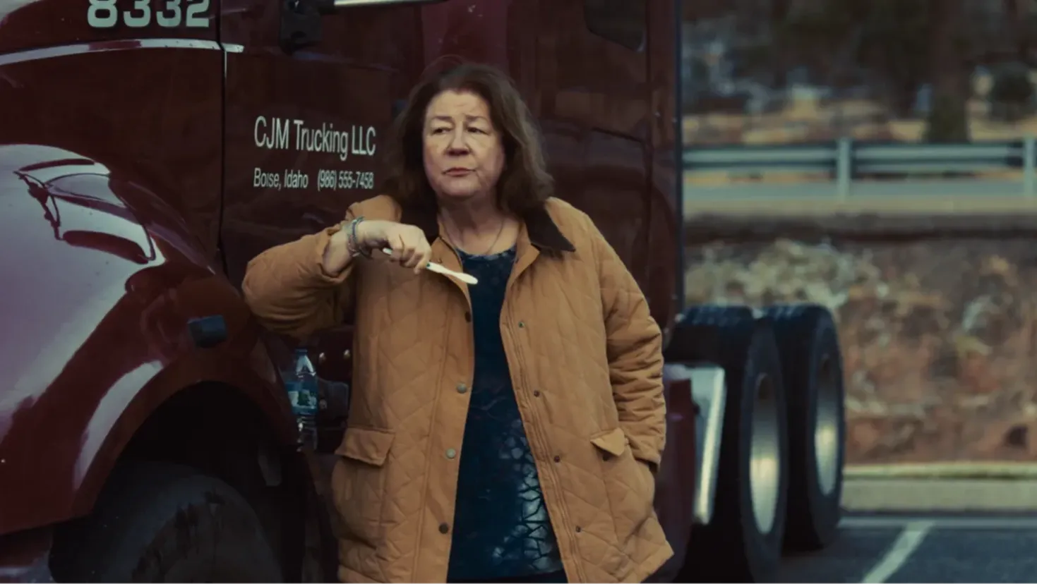 A woman standing at the side of her truck holding a toothbrush