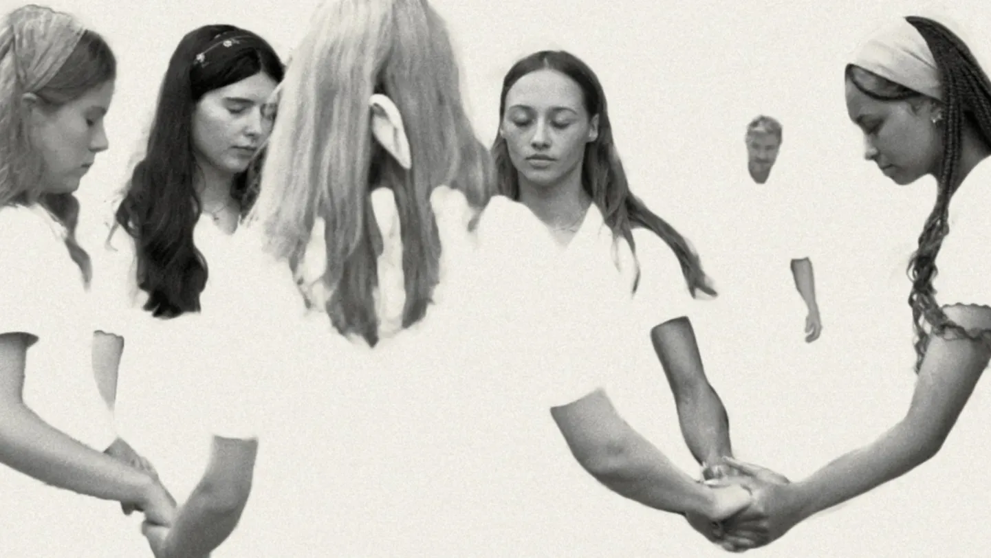 Black and white stylised image. A group of young women praying, holding hands with closed eyes. A man is in the background.