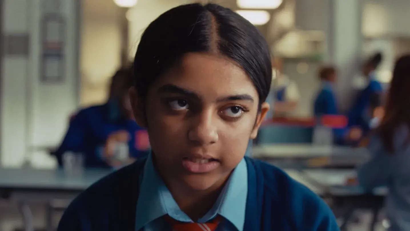 A young girl in school uniform sitting in the school canteen