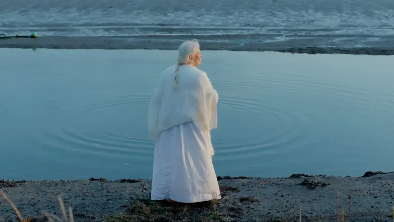 A woman throws stones into the creek at sunset