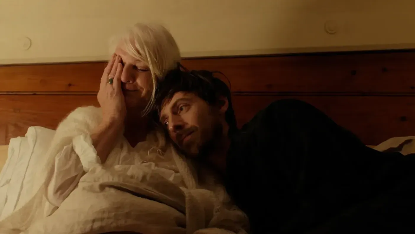 A woman and a man lie on a bed together.