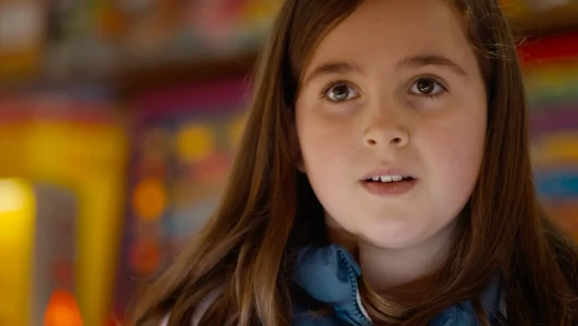 A young girl with the lights of an amusement arcade behind her