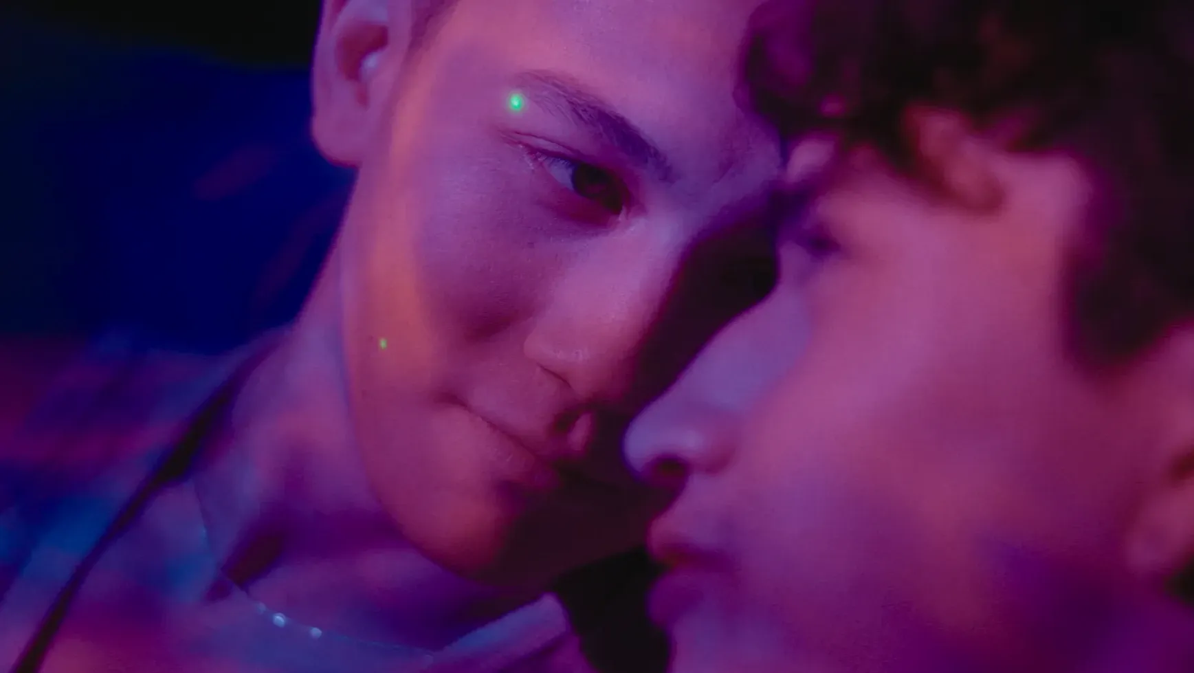 Two men looking at each other underneath purple lighting