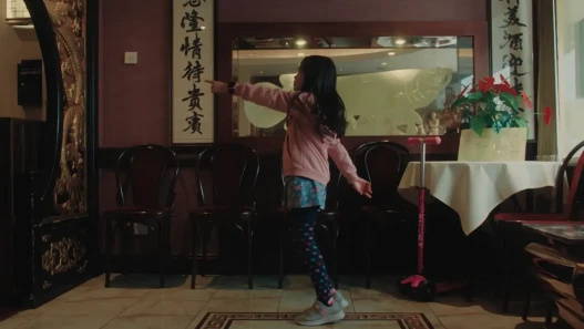 A young girl, pointing at something inside a Chinese restaurant lobby.