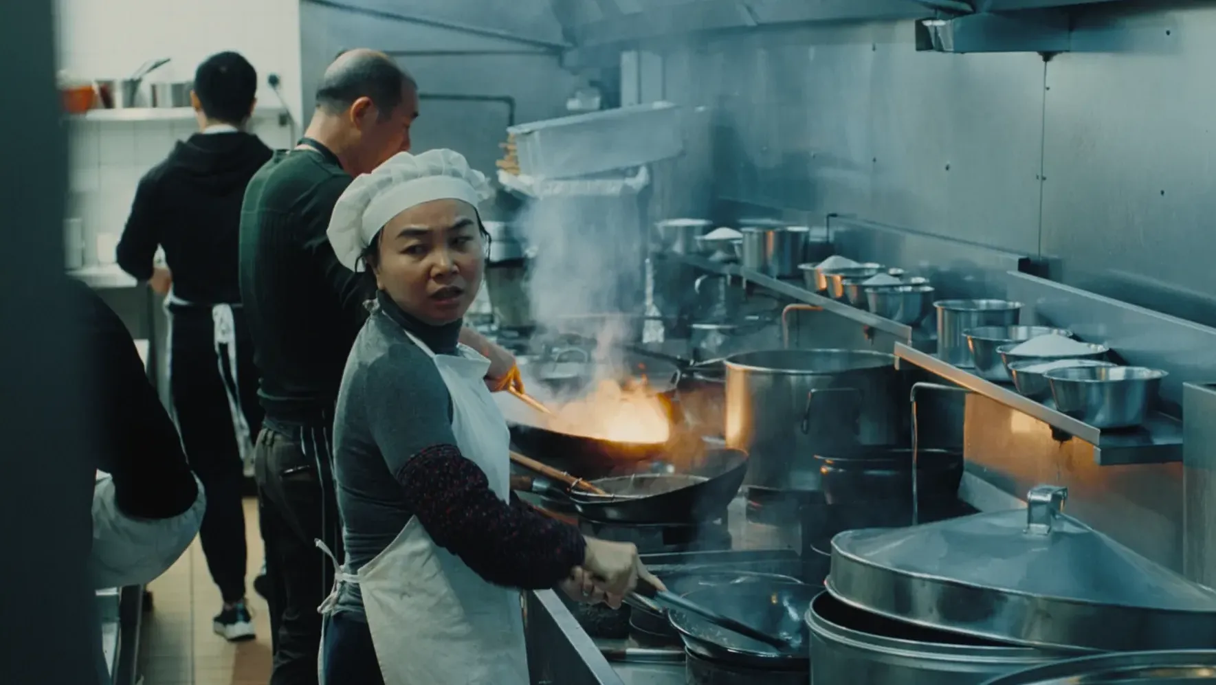 A female cook searching for ingredients in a busy Chinese kitchen.