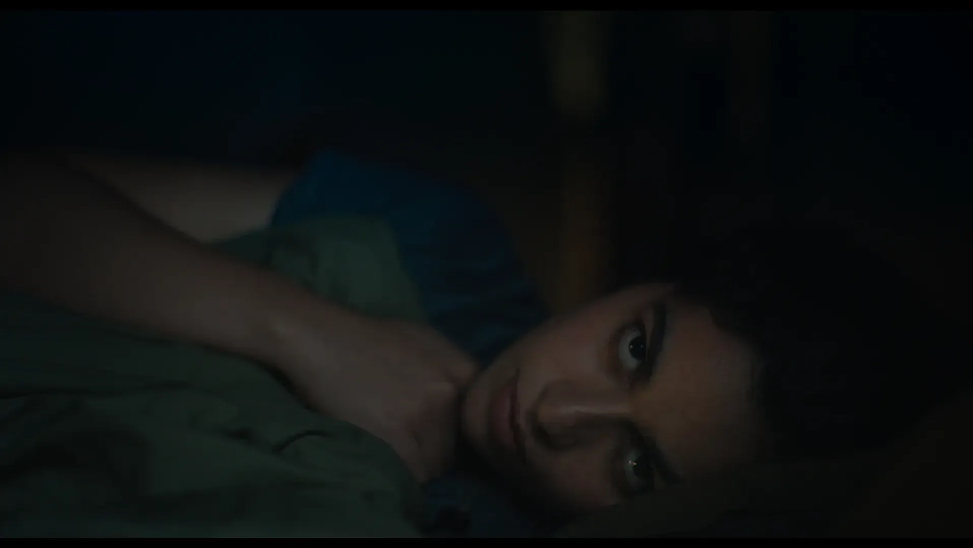 A woman lying in bed staring through the camera