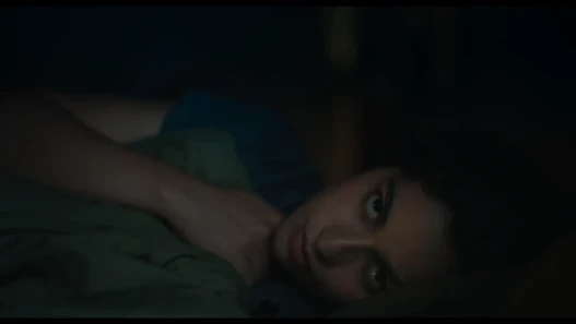A woman lying in bed staring through the camera