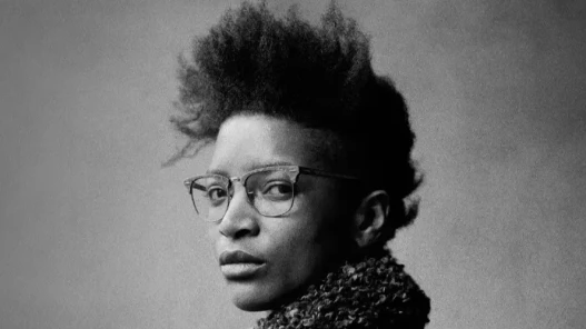 Black and white image. A woman wearing glasses looks directly into the camera