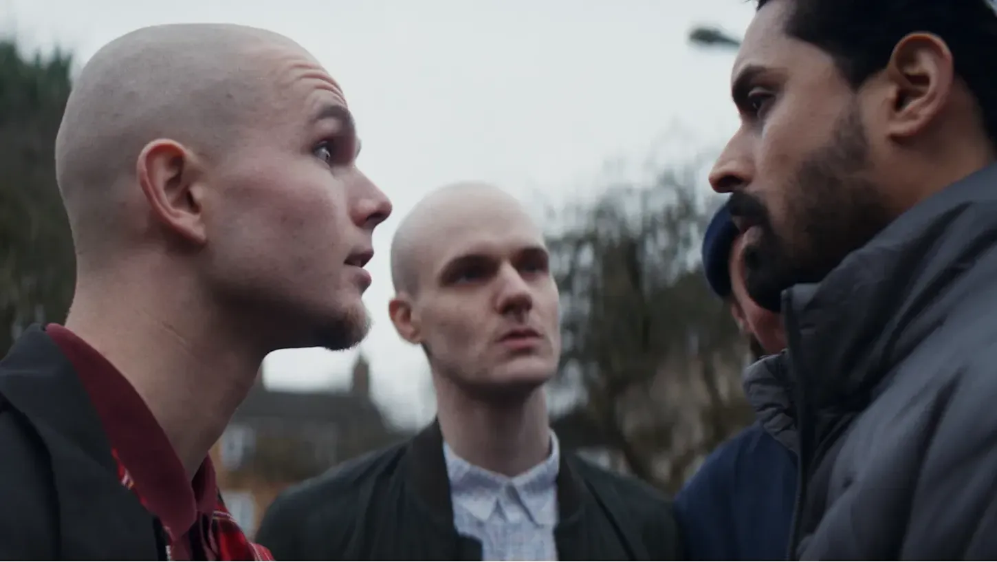 Image from a dramatic reconstruction - Two white skinhead males are staring aggressively at a black man.
