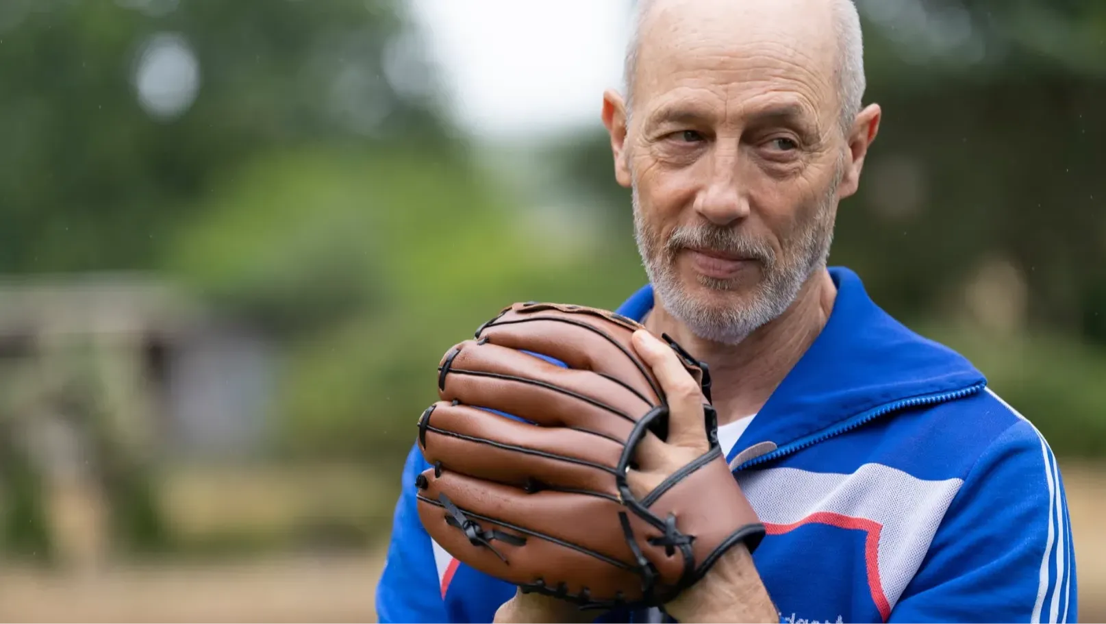 An older man wearing a sports top and baseball glove.