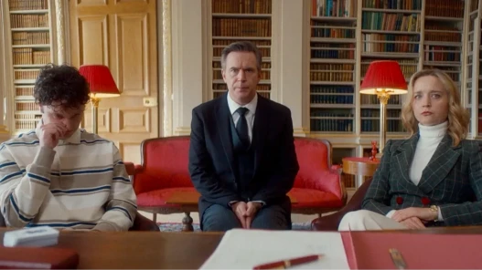 Two men and a woman sit in front of a desk looking concerned
