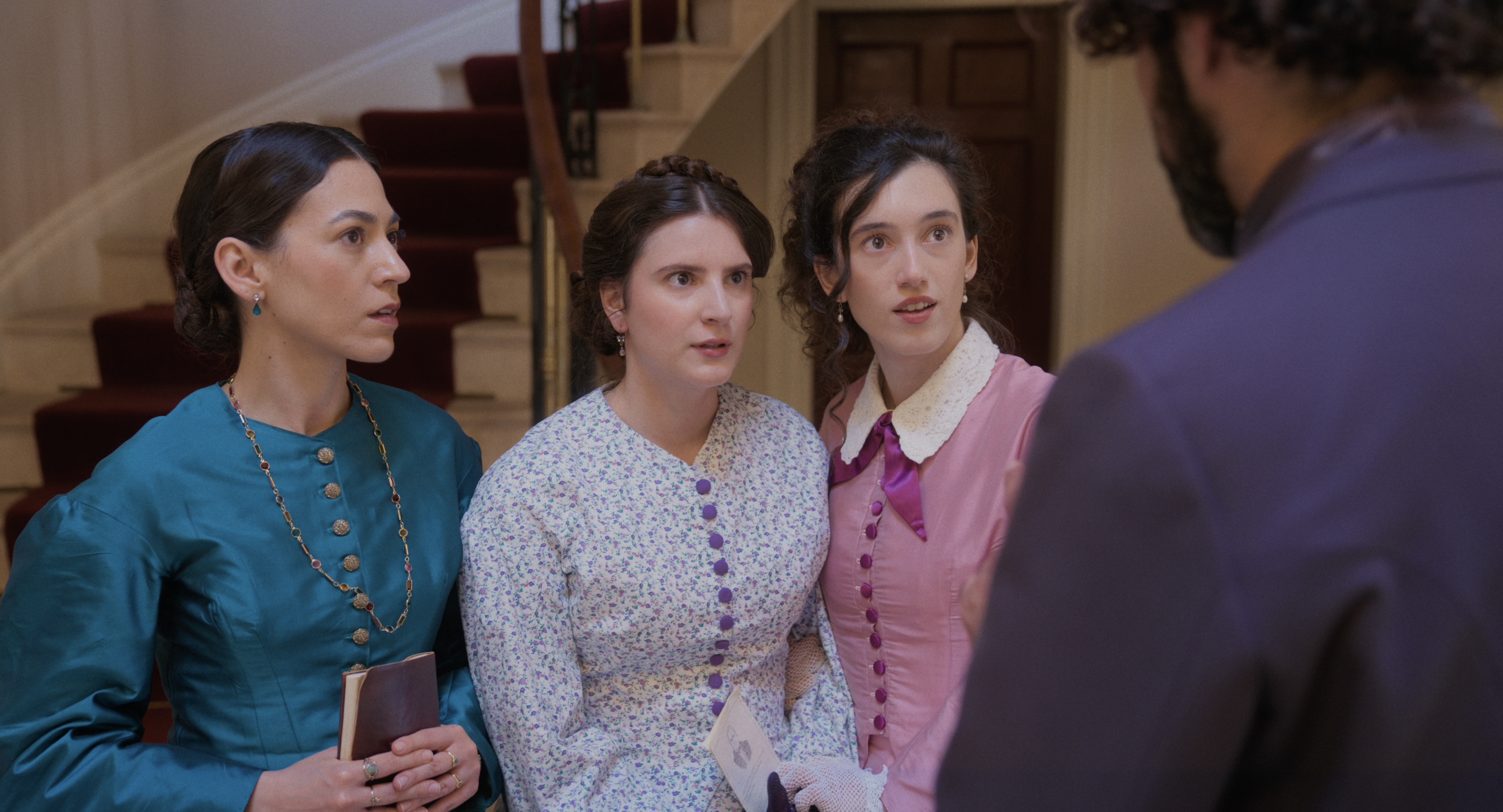 Three women talking to a bearded man in a blue jacket with his back to camera. 