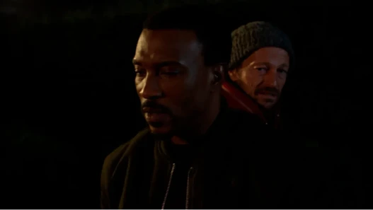 Two men's faces in shadows with low light and a black background