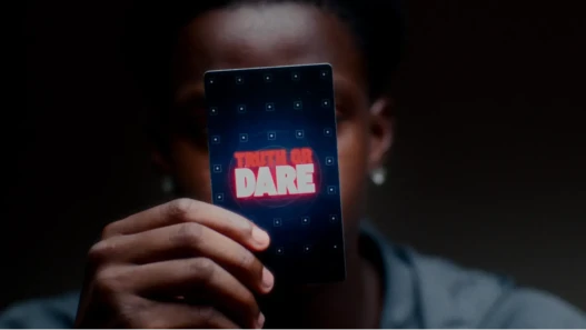 A young man holds up a truth or dare playing card