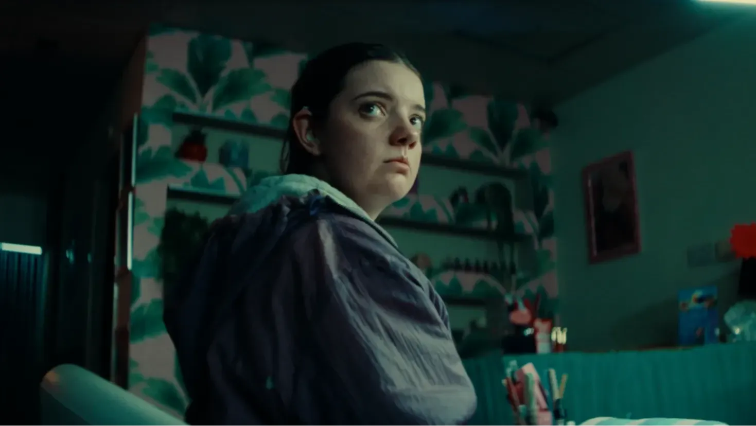 A young girl stares solemnly towards the door of a nail salon.