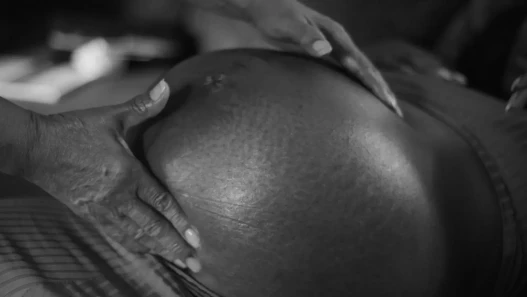 Hands placed on a very pregnant stomach