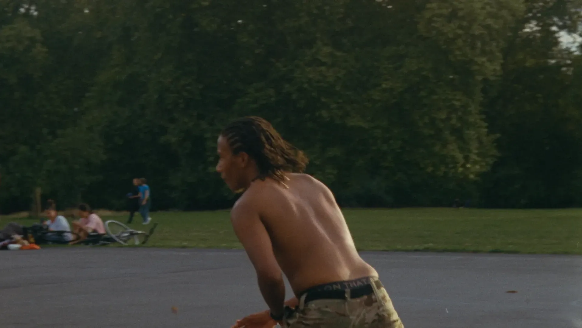 A young black man is shown running across an outdoor basketball court