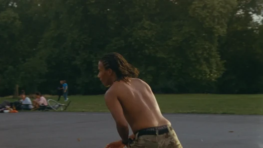 A young black man is shown running across an outdoor basketball court