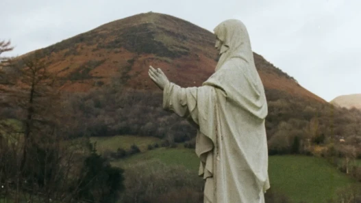 Virgin Mary statue in front of a hill, an overcast sky